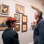 Portraits that visiting professor Jason Scott collected from thrift stores attract faculty members Beth Dougherty, Daniel Youd, and John Rapp at the “Beloit Collects!” opening.