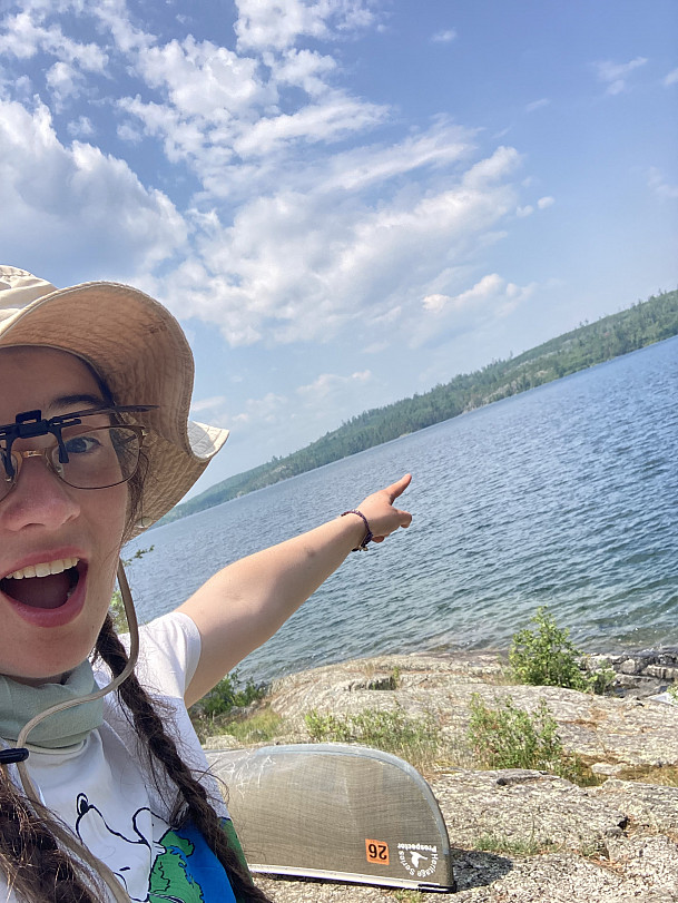 Maggie Joyce '27 pointing at Canada off of Knife Lake.