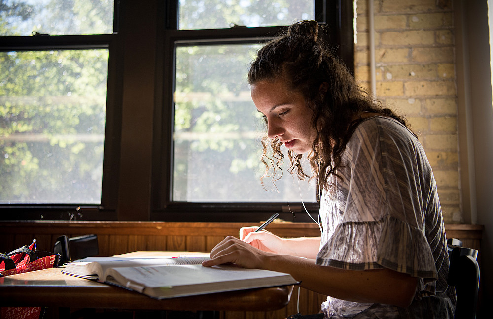 A Beloit College student studies from a large book in the sunshine.