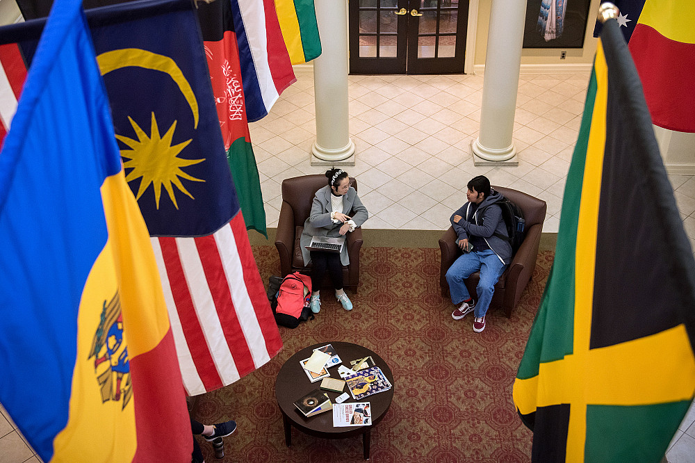Students talk together underneath the flags of many countries in Beloit College's World Affairs Center.