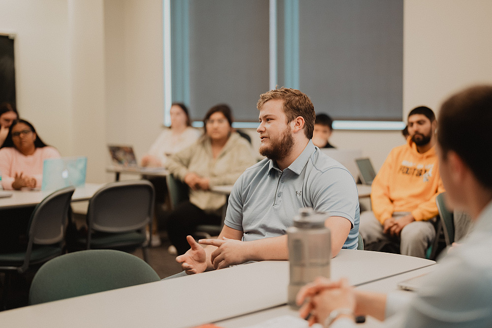 A Beloit College student speaks in the middle of class, attentively listened to by their peers.