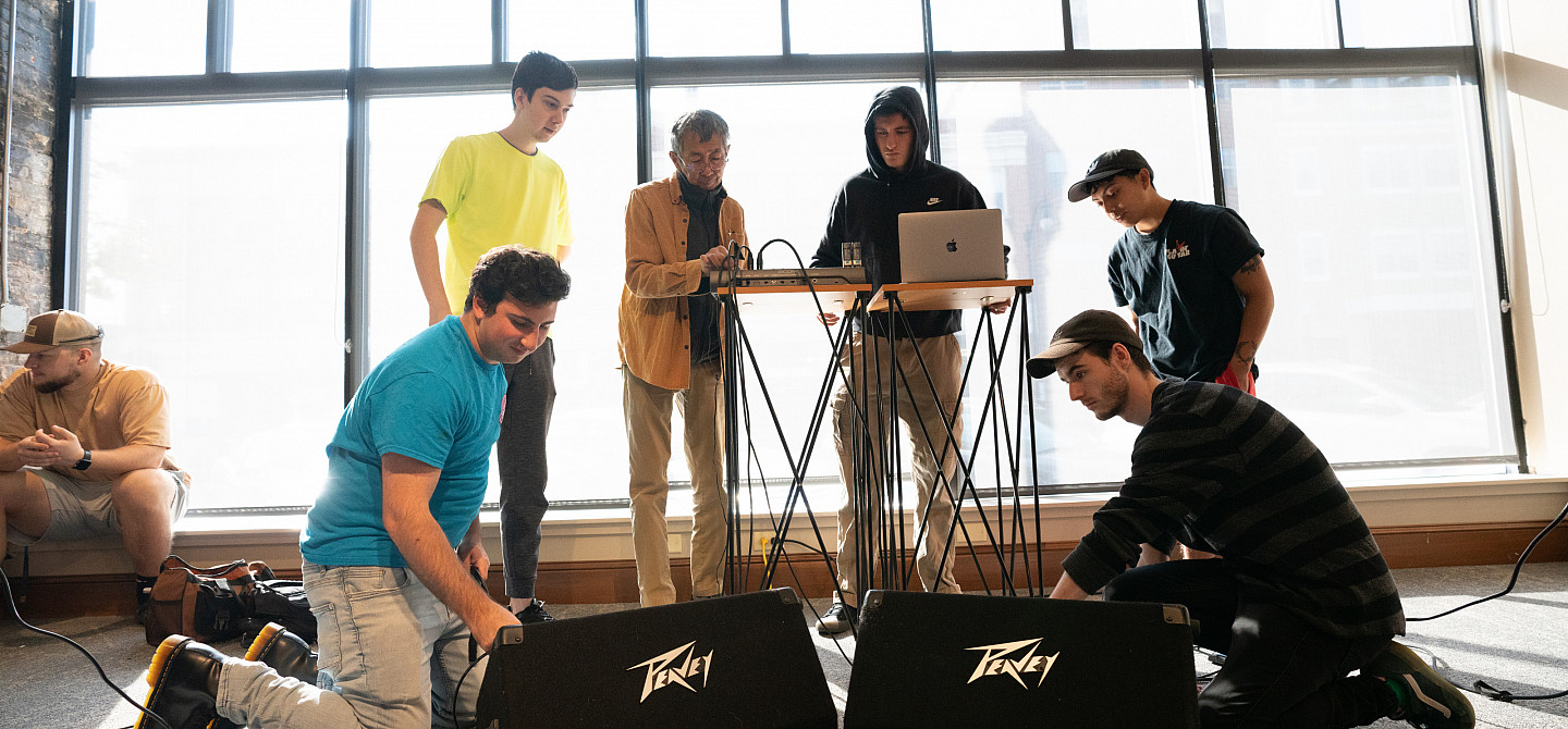 Students work with a professor on how to best arrange sound equipment.