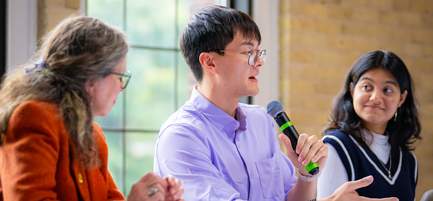 A student speaks into a microphone during an alumni event.