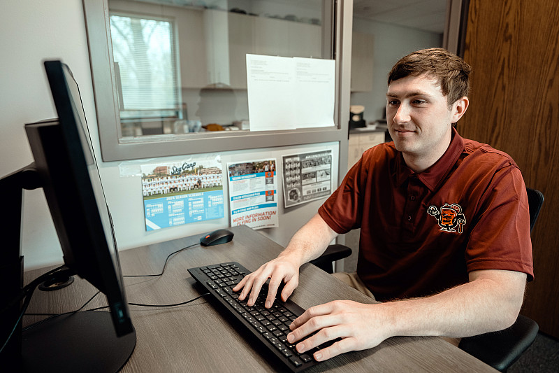 A Beloit College student works in an office of the Beloit Sky Carp as part of the Concierge Internship Program.