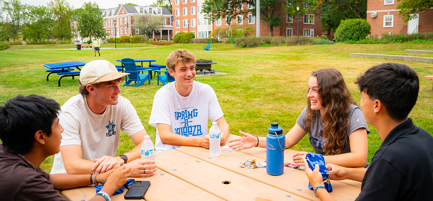 Students sitting at an outdoor table and talking.