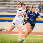 Beloit College Women's Lacrosse player Maya DeGeorge runs down the field with a opponent giving chase.