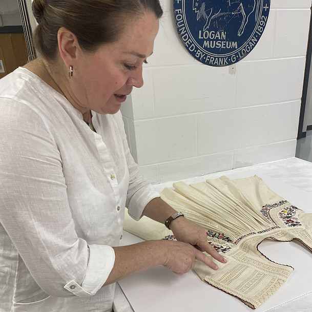 Logan Museum Director Nicolette Meister displays a Mexican blouse crafted around 1950, with bright flower blooms in pink, purple and yell...