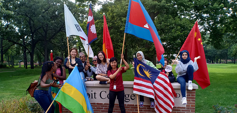 International students wave their flags in front of the Beloit College sign following Convocation...