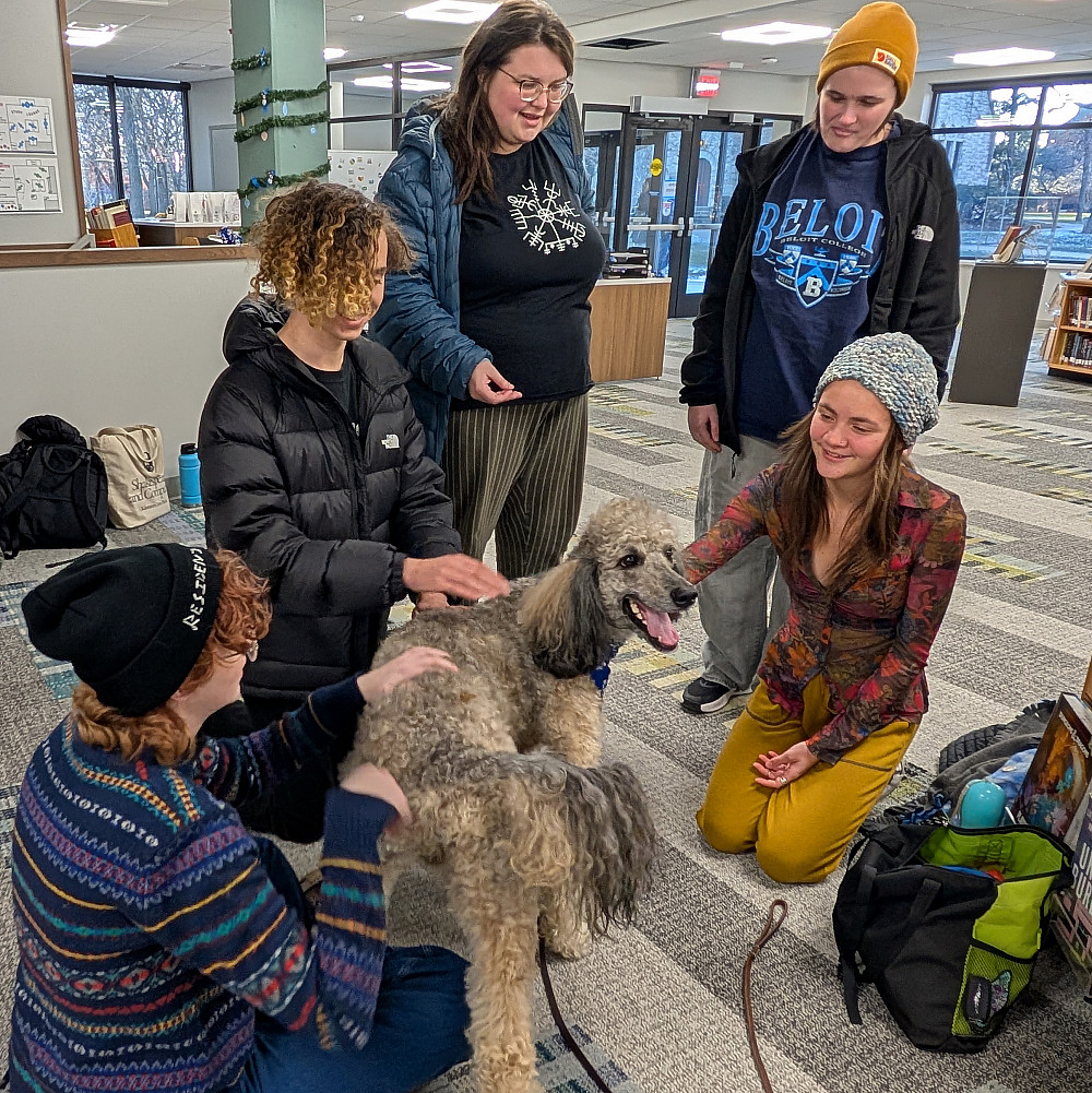 PXL 20241205 212148130 Photo of students petting therapy dog Koda in the library.