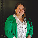 a women in a white shirt and green cardigan looks at the camera