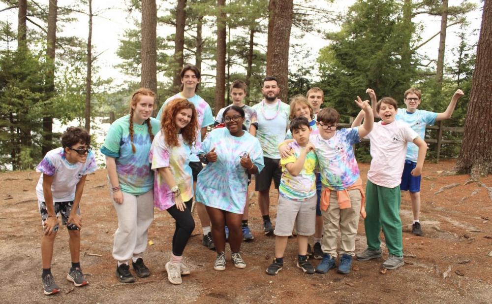 Kids pose and smile for a picture in the woods.