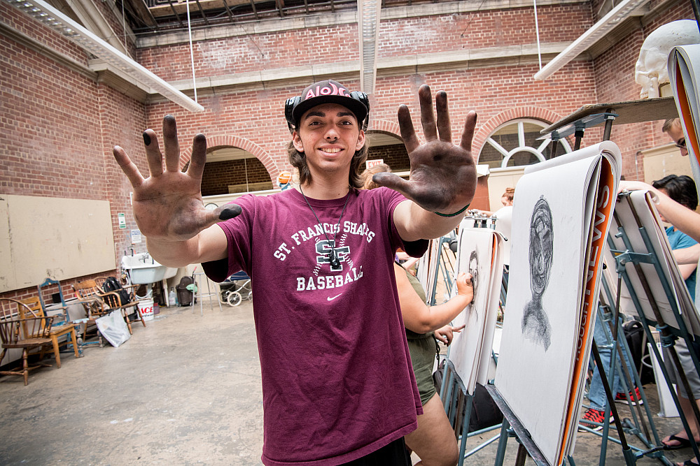 A Beloit student shows his charcoal covered hands after doing a sketch in his drawing class. 