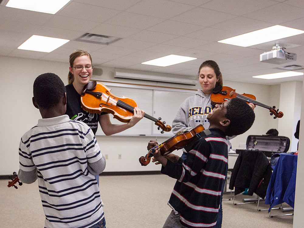 Beloit College music students teach violin lessons to 2 young boys from the Beloit community.