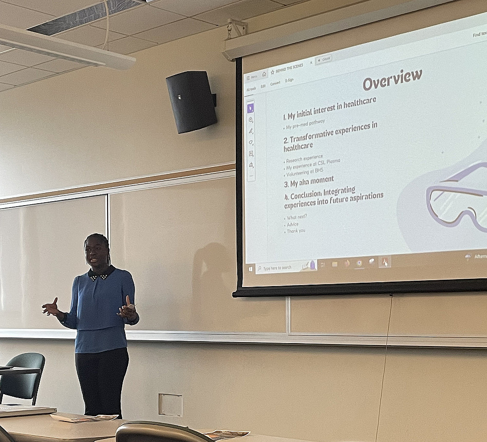 Ama Ameyaw'25 stands in front of a projector talking through a slideshow about her local healthcare experiences.