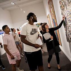 Collections manager and exhibitions coordinator Christa Story points out specific details on a pi...