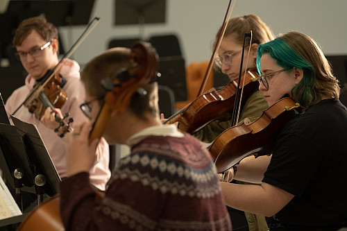 A group of students with violins and violas playing together during ensemble practice.