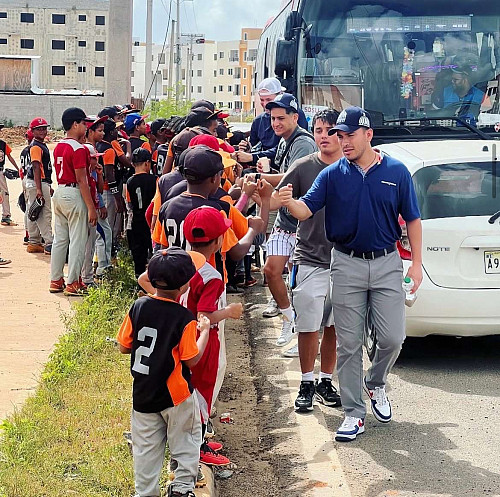 Kids standing in line high-fiving college students.