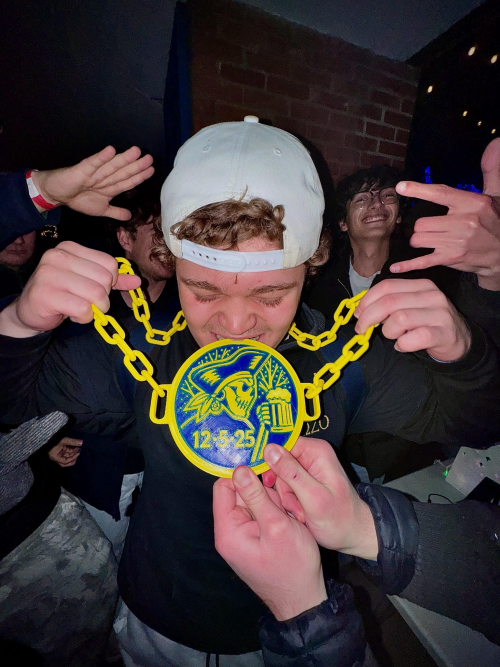 A student is looking down as he gets a plastic prize chain put around his neck.