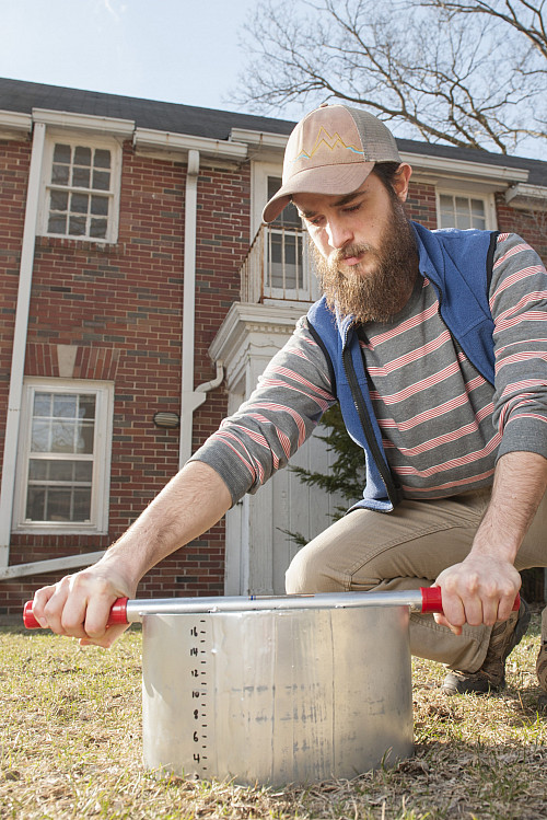    A Beloit sustainability student takes soil measurements with a double ring infiltrometer. 