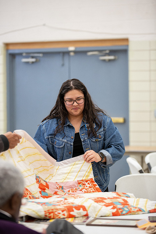 Partida inspects a family quilt brought during the History Harvest, spring 2019.