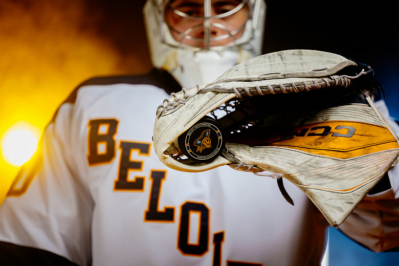 A Beloit College Men's Hockey goaltender holding a Buccaneers puck in their glove.