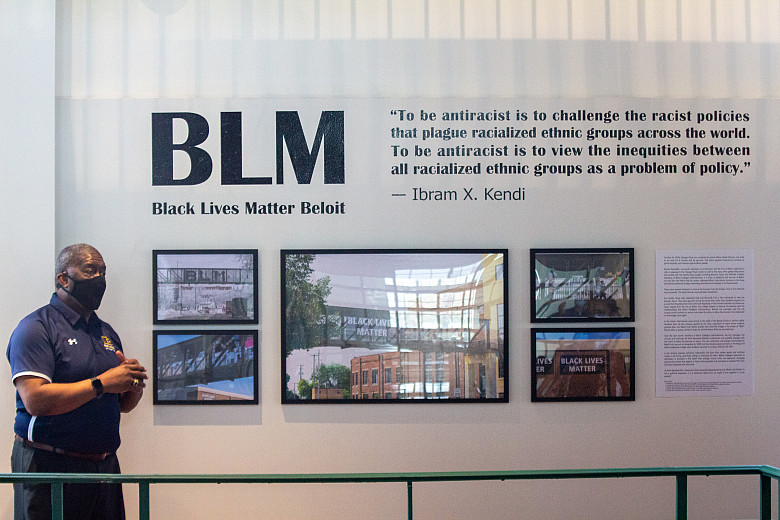 Dean of Students Cecil Youngblood stands in front of the new BLM photo gallery display in the Powerhouse. 