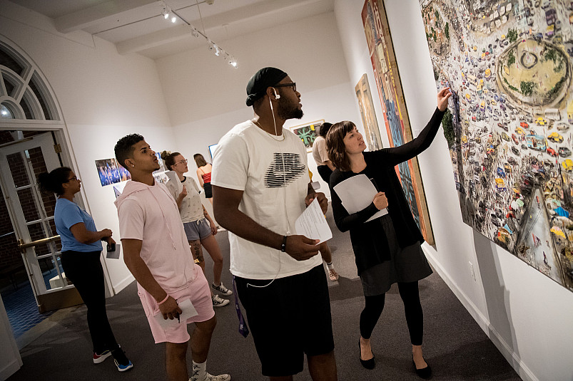 Collections manager and exhibitions coordinator Christa Story points out specific details on a piece of art to students at the 