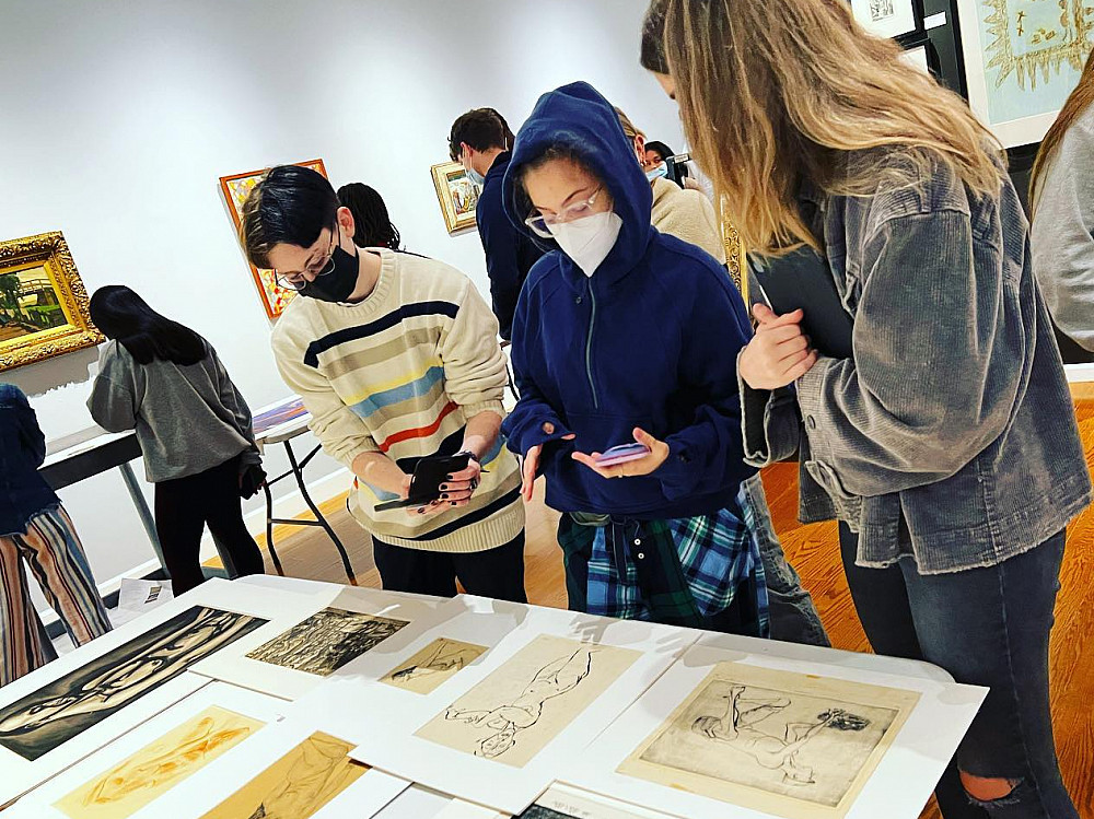 Students look at artwork on a table in the Wright Museum of Art.