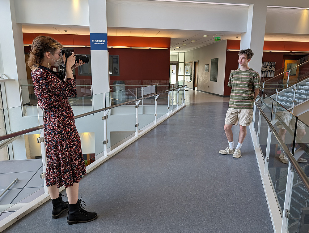 one person holding a camera takes a photo of another person standing