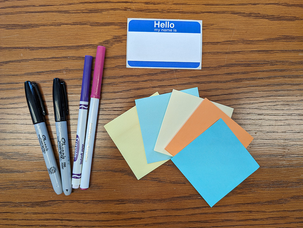 picture of stickies, markers, and a name tag on a table.