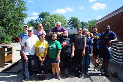 people standing in front of a dumpster