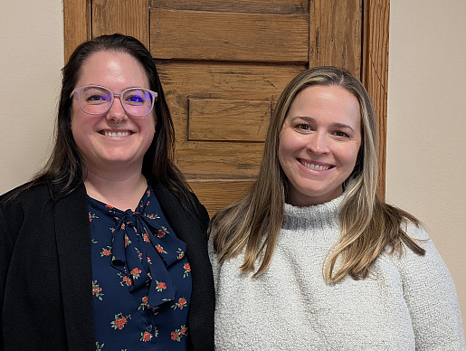 two women stand next to each other smiling