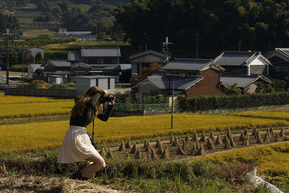 A student photographs of a luscious and green countryside landscape in rural Japan with a professional camera.