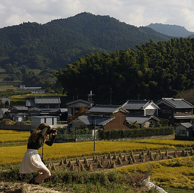 A student photographs of a luscious and green countryside landscape in rural Japan with a profess...