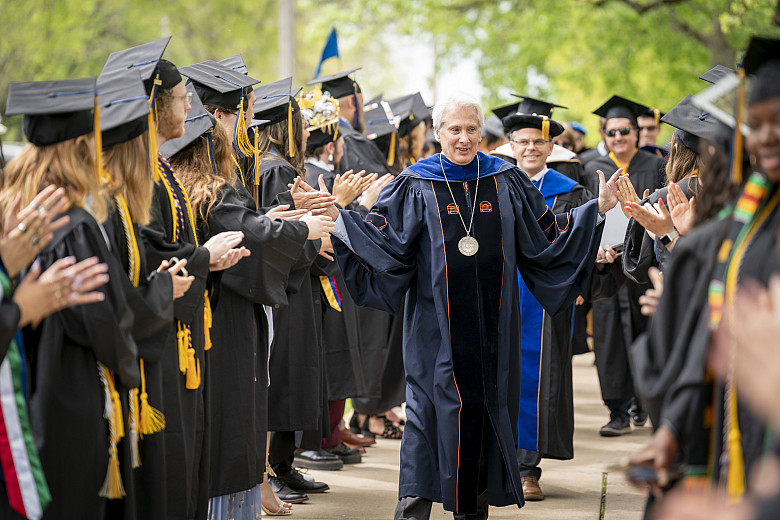 Beloit College President Scott Bierman high-fives senior before the commencement on May 15, 2022 begins.