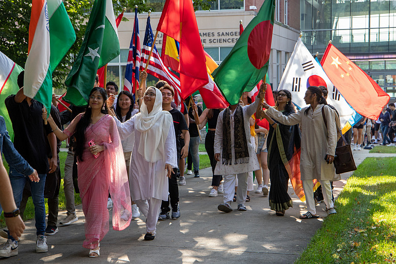 International students lead the Convocation march, proudly hoisting their countries' flags.