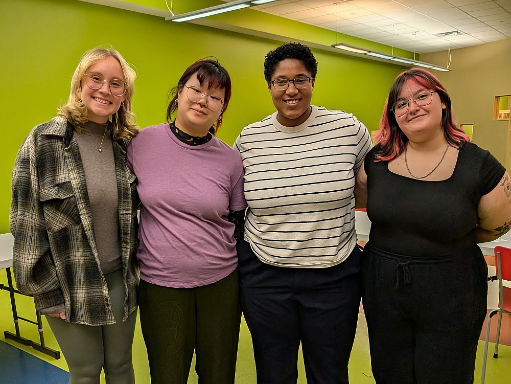 4 students stand together in a program room