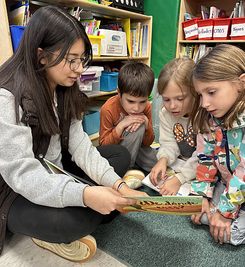 Rosa Solis'26 reads ¿De dónde eres? to three Todd Elementary students.