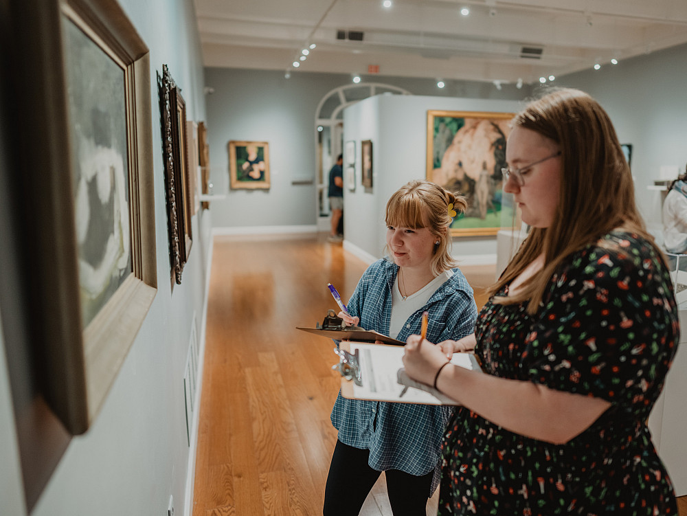 Two students studying artwork inside the Wright Museum of Art.