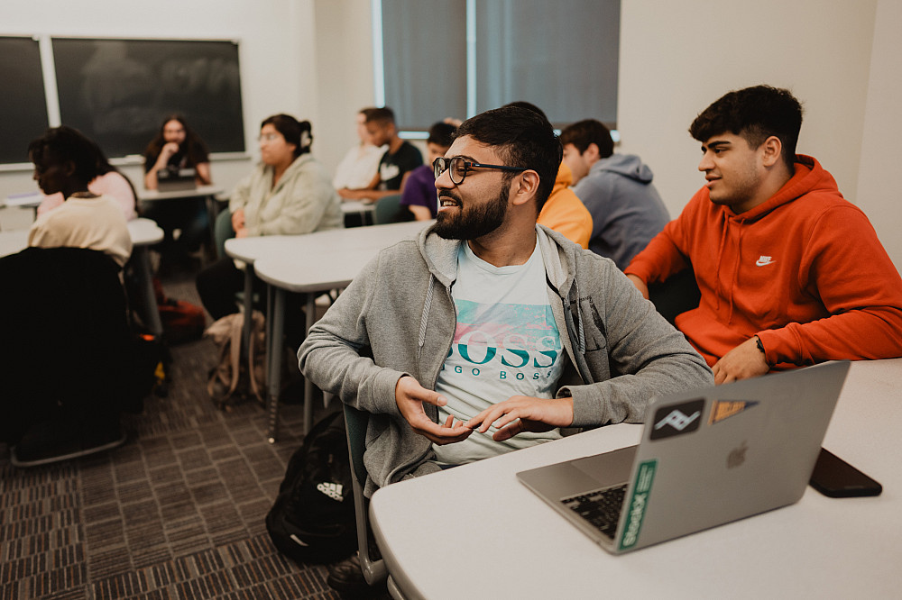 A student speaks to the room in the middle of an economics class.