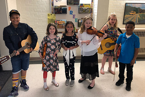 Turtle Tunes students stand together with their instruments.