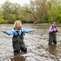 Three students test the water movement of a stream during their field study for a hydrogeology class.