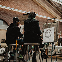 Two students sit together while making self portraits in the Wright Museum's art studio.