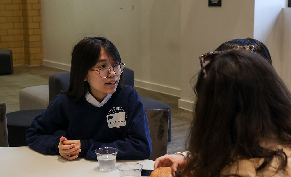 student sitting at a table in the turbine gallery talking with other students