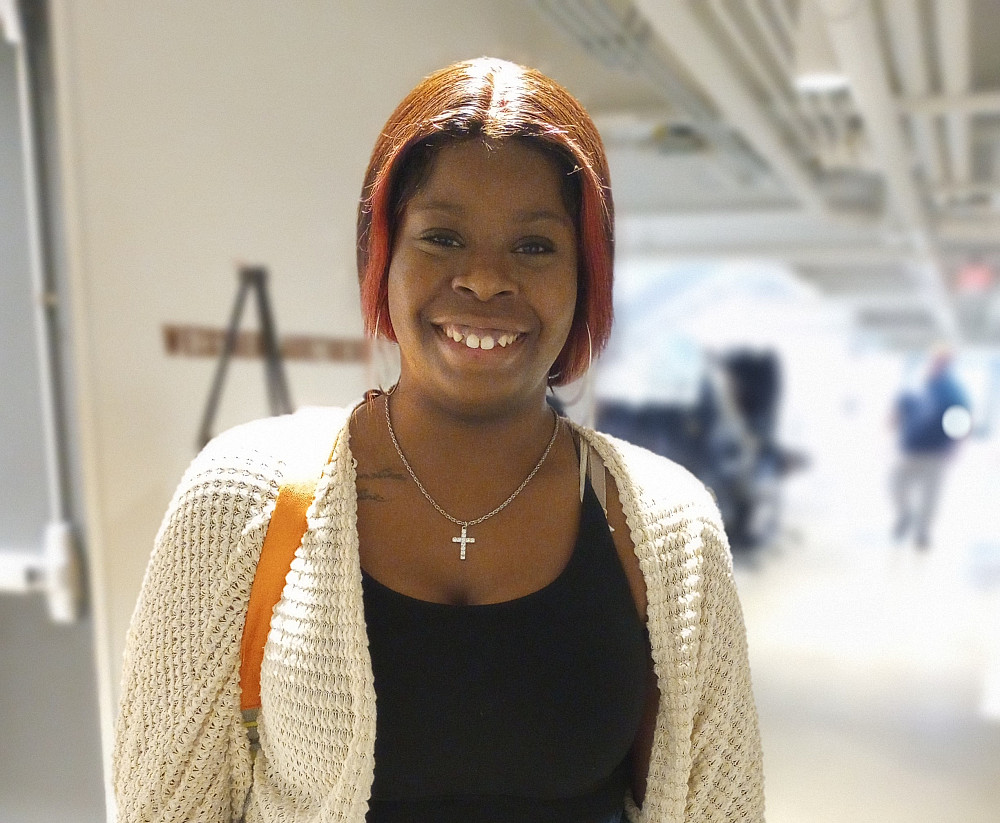 student with a white sweater standing in a hallway in the Powerhouse