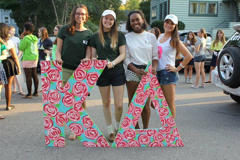 Members of Kappa Delta holding their letters while preparing for a homecoming parade.