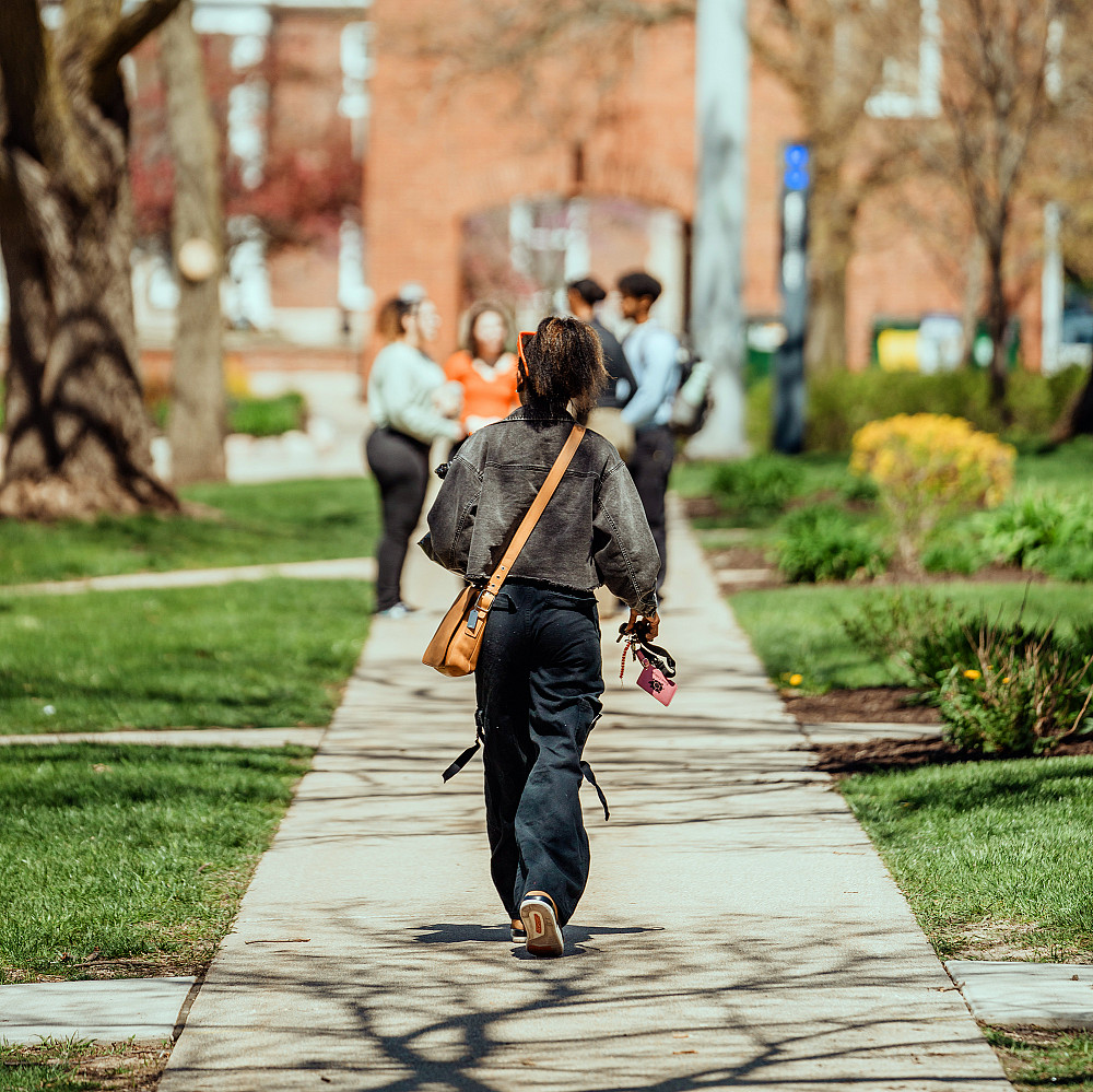 A student walks down College Street towards a group of friends.