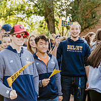 Students holding pennants at homecoming A crowd of students smiling with Beloit pennants and shirts at the homecoming parade.