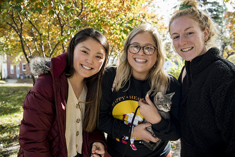 3 students smiling with trees in the background.
