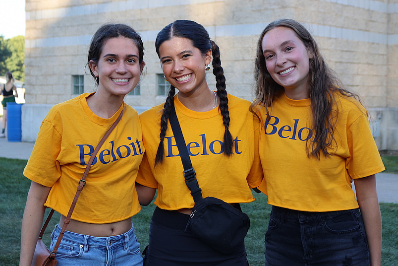 Three students smiling and wearing matching gold Beloit College t-shirts.